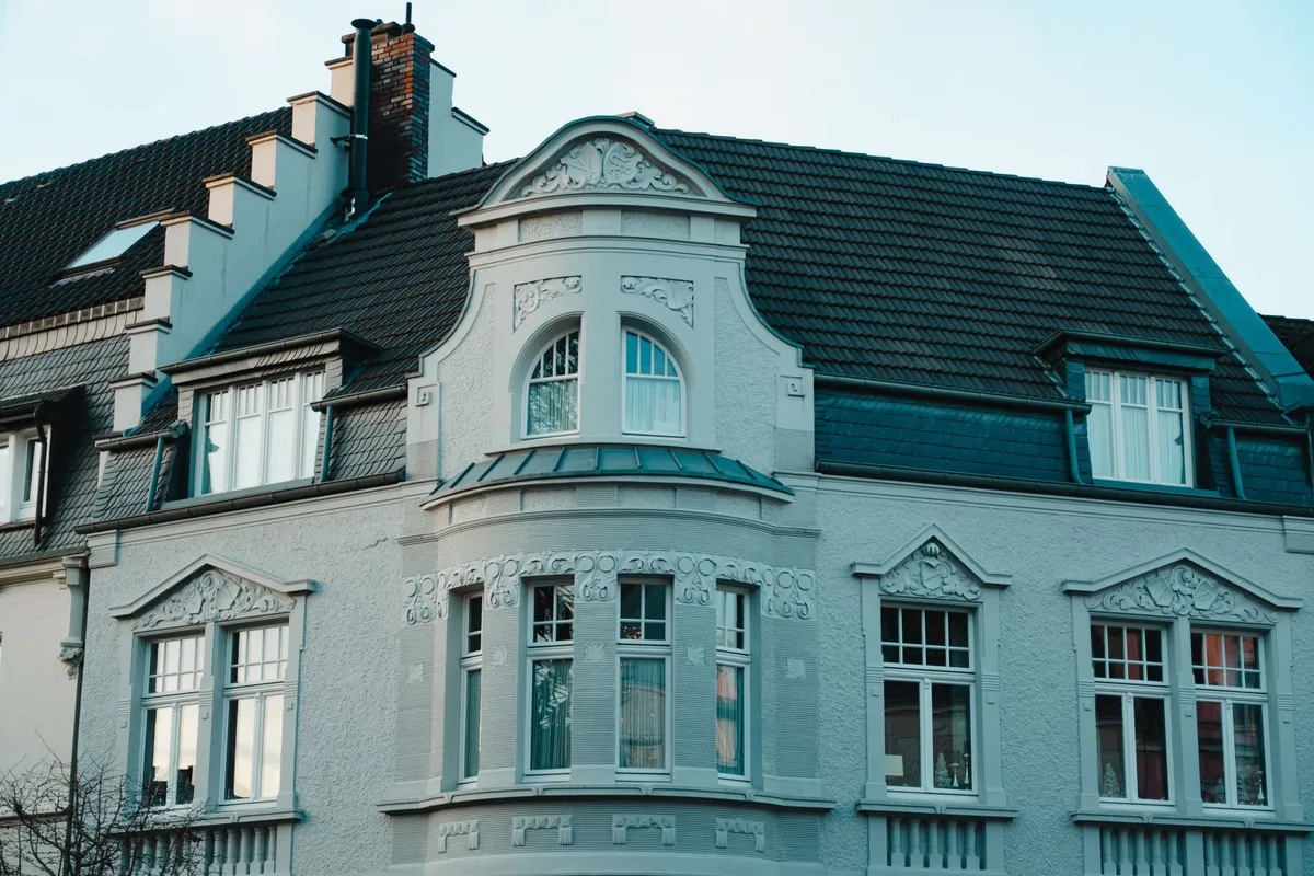 Eckhaus der Gründerzeit mit Erker, Stuckgiebeln über den Fenstern und dunklem Ziegeldach